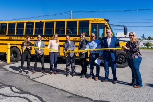 Group cutting a yellow ribbon to launch new electric school buses