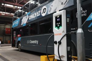 Zenobē-branded electric bus charger inside National Express Coventry depot, with a double-decker electric bus plugged in for charging.